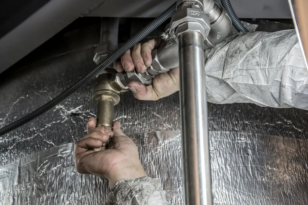 Plumber inspecting residential pipes in a Rapid City home to locate a frozen section